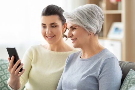 daughter and senior mother with smartphone at home
