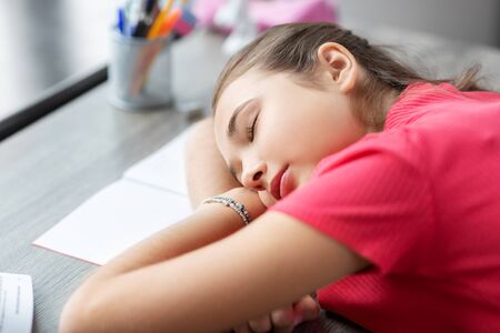 tired student girl sleeping on table at home