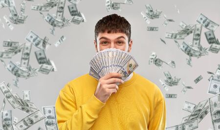 happy young man in yellow sweatshirt with money