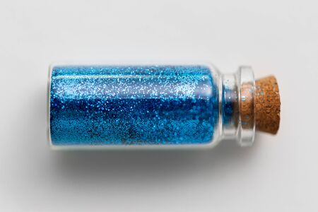 blue glitters in bottle over white backgroundの写真素材