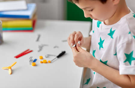 childhood, imagination and dream concept - close up of little boy playing with airplane toy on bed...