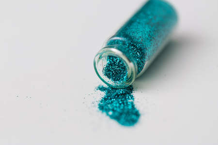 blue glitters poured from small glass bottleの写真素材