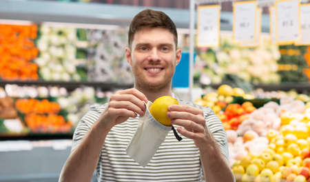 smiling man putting lemon in reusable grocery toteの写真素材