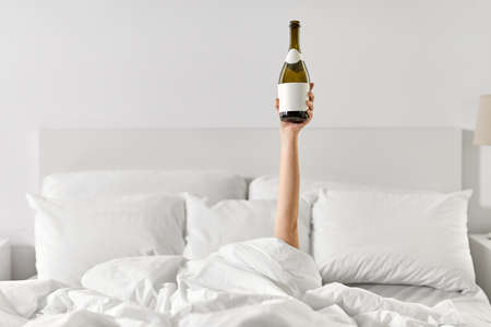 hand of woman lying in bed with champagneの写真素材