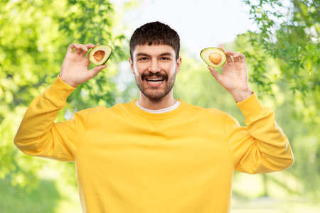 happy young man in yellow sweatshirt with avocadoの写真素材
