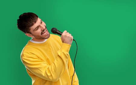 man in yellow sweatshirt with microphone singingの写真素材