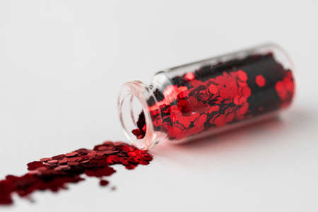 red glitters poured from small glass bottleの写真素材