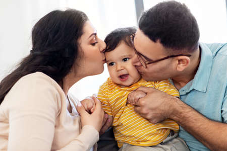 happy mother and father kissing baby son at homeの写真素材