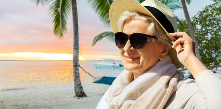 people and leisure concept - portrait of happy senior woman in sunglasses and straw hat over...