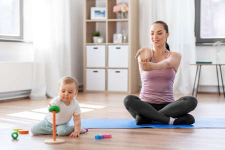 happy mother with little baby exercising at homeの写真素材