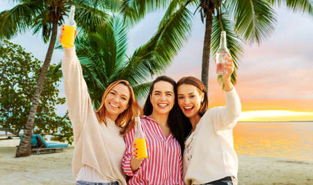 young women toasting non alcoholic drinks on beachの写真素材