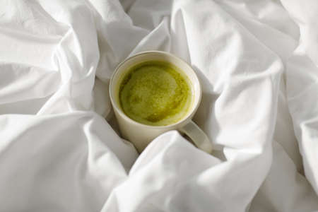 cup of matcha tea in bed at homeの写真素材