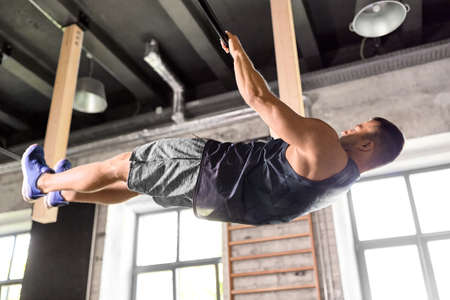 young man exercising on horizontal bar in gym