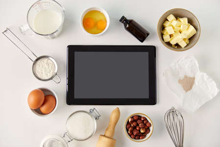 tablet computer and cooking ingredients on table