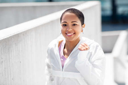fitness, sport and healthy lifestyle concept - happy smiling young african american woman running...