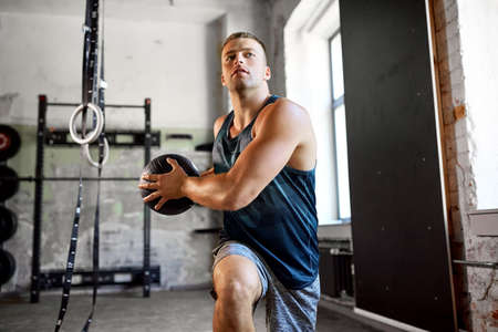 young man exercising with medicine ball in gym