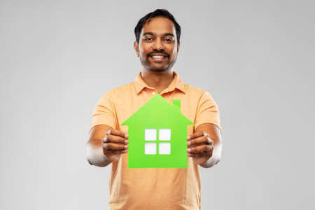 smiling indian man holding green house iconの写真素材