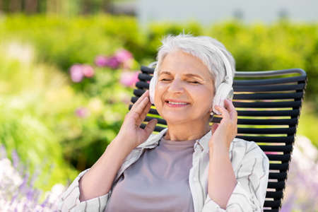 happy senior woman with headphones at garden