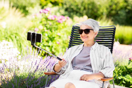 happy senior woman taking selfie at summer garden