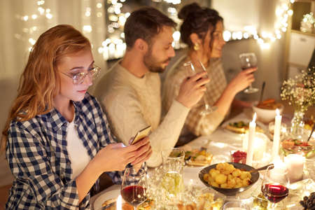 woman with smartphone at dinner party with friendsの写真素材