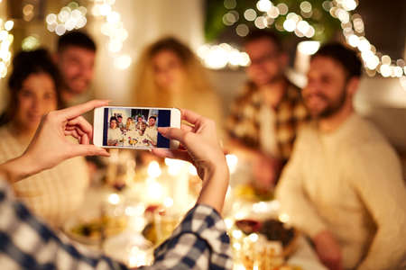 friends photographing at christmas dinner partyの写真素材