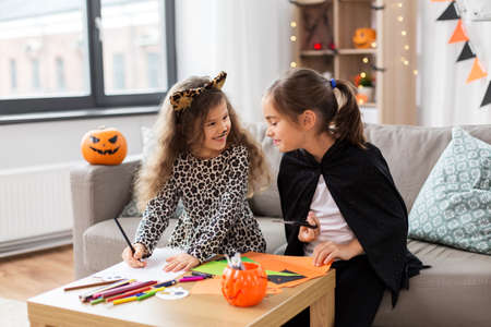 girls in halloween costumes doing crafts at homeの写真素材