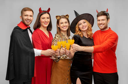 happy friends in halloween costumes over grey