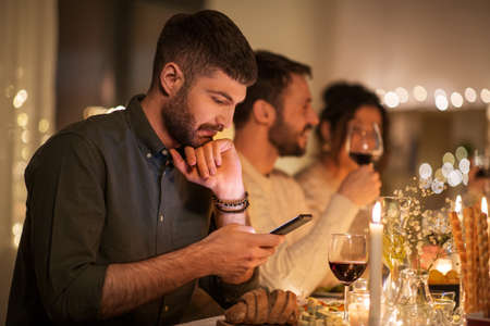 man with smartphone at dinner party with friendsの写真素材