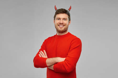 happy man in halloween costume of devil over greyの写真素材