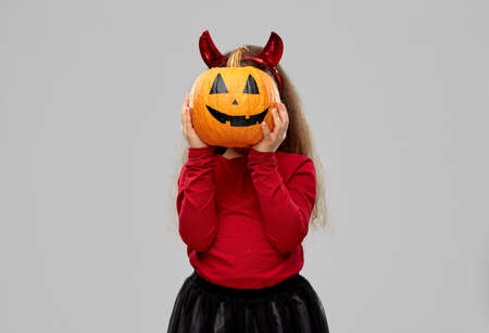 girl in halloween costume with jack-o-lantern