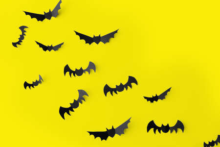 flock of black paper bats over yellow backgroundの写真素材