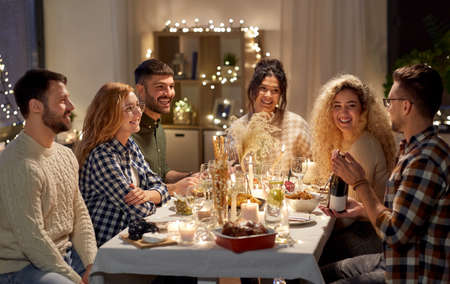 happy friends with red wine at christmas partyの写真素材