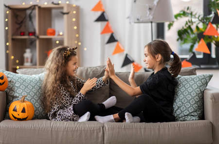 girls in halloween costumes playing game at homeの写真素材