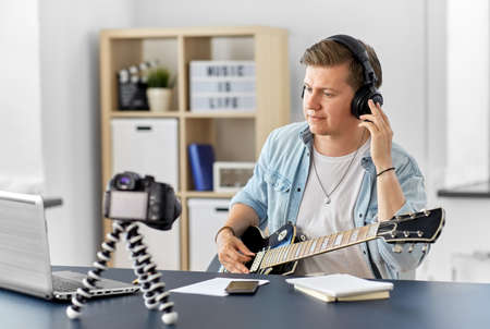 man or blogger with camera playing guitar at home