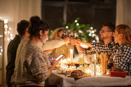 woman with smartphone at dinner party with friends