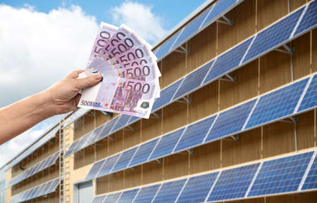 hands holding money over solar panelsの写真素材