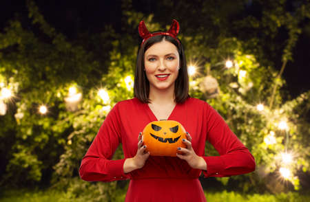 woman in halloween costume of devil with pumpkin