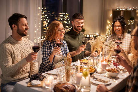 happy friends drinking red wine at christmas partyの写真素材