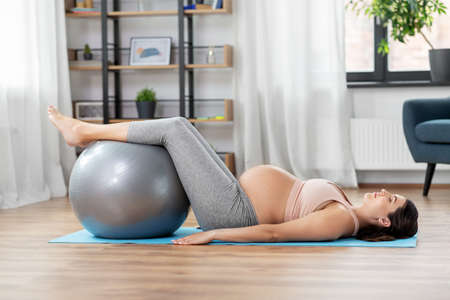 pregnant woman training with fitness ball at homeの写真素材