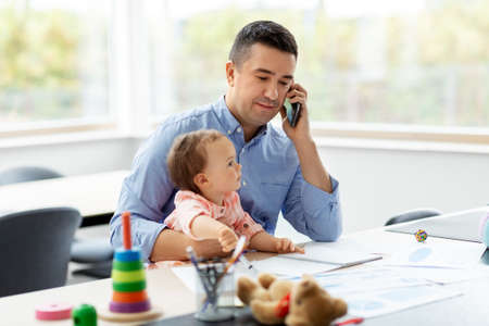 father with baby calling on phone at home officeの写真素材