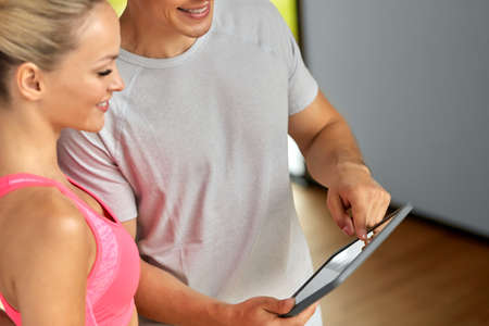 close up of man and woman with tablet pc in gym