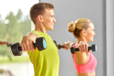 close up of smiling woman with dumbbell in gymの写真素材