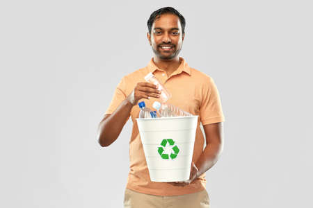smiling young indian man sorting plastic wasteの写真素材