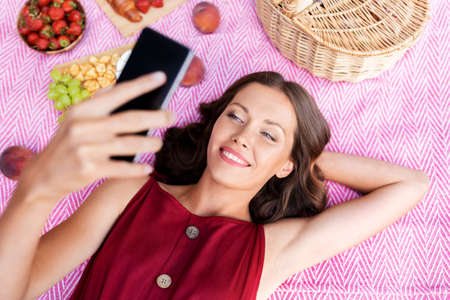 happy woman with smartphone taking selfie at park