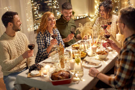 happy friends drinking red wine at christmas party