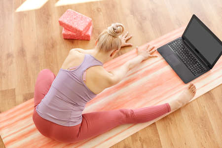 woman with laptop exercising at yoga studio