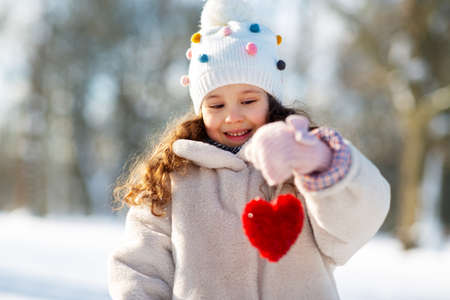 happy little girl with heart outdoors in winterの写真素材