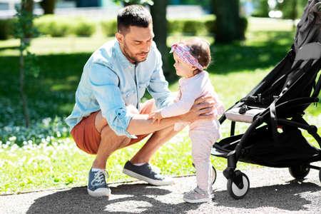 happy father with child in stroller at summer park