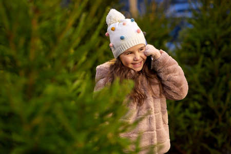 girl calling on smartphone over christmas trees