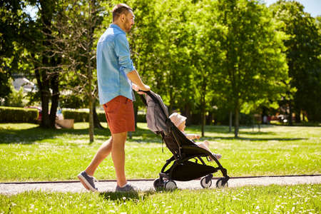 happy father with child in stroller at summer parkの写真素材